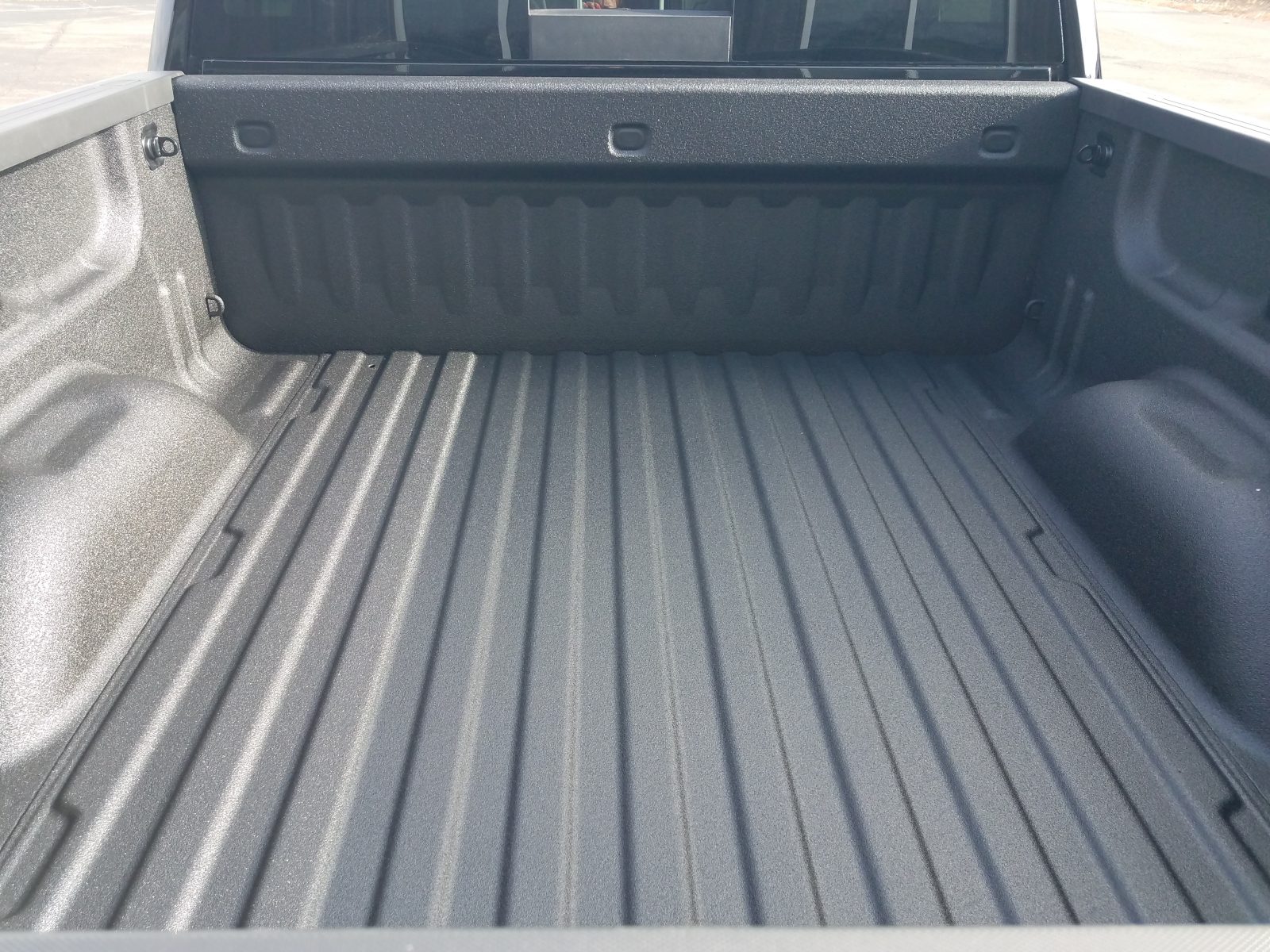 Close-up of a textured spray-applied polyurea bed liner covering a truck bed floor and tailgate