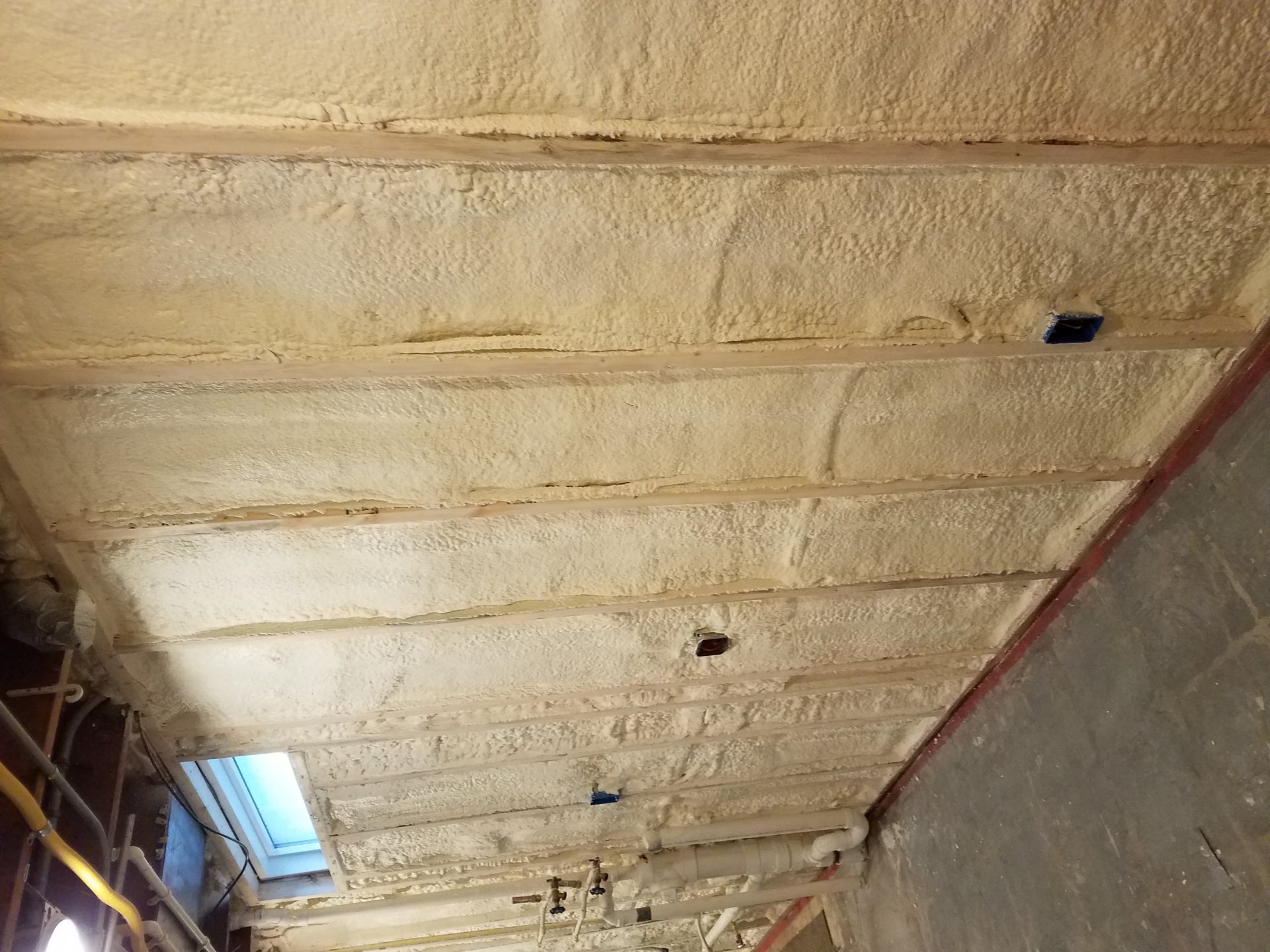 Closed-cell spray foam insulation applied between floor joists