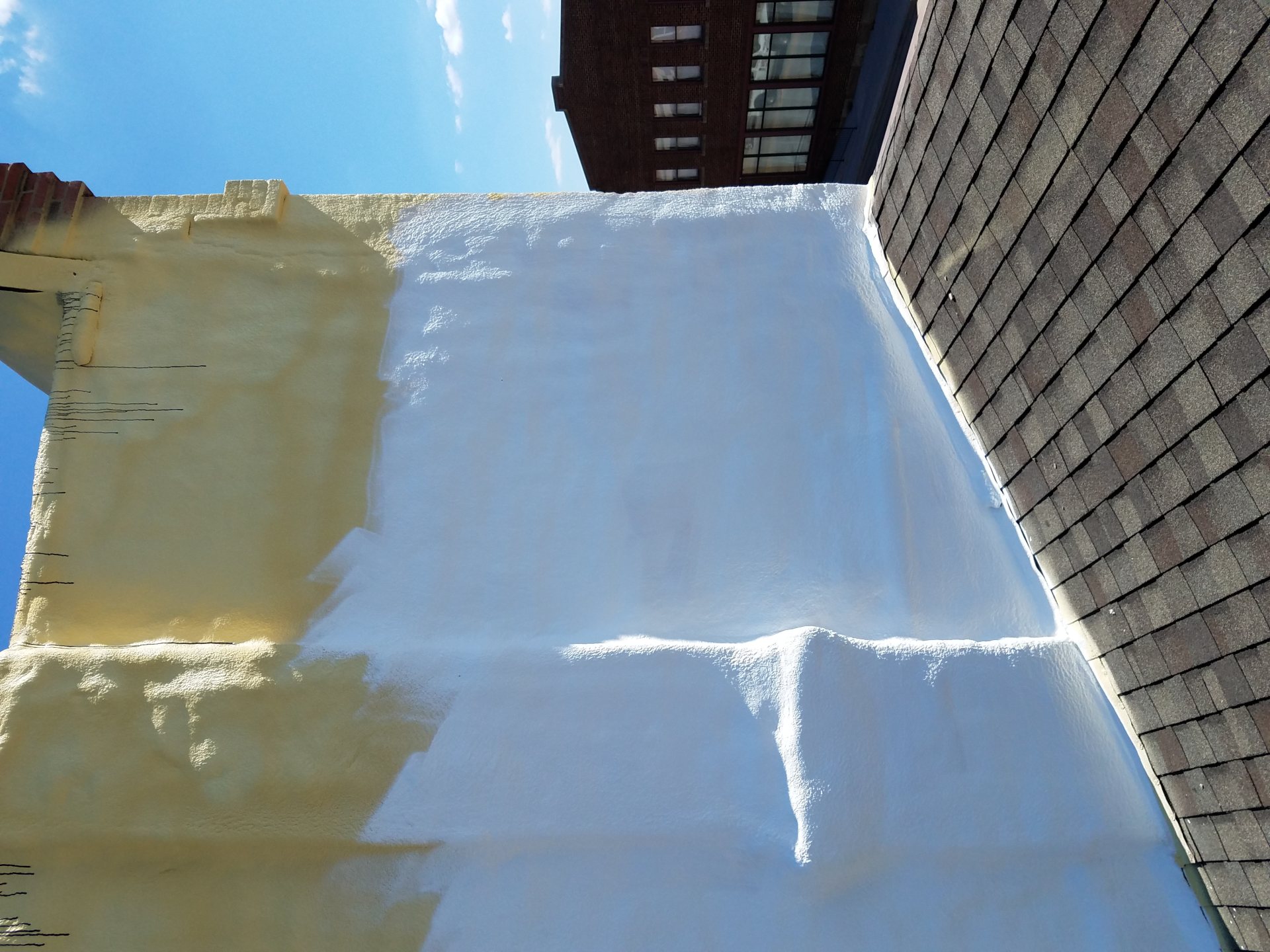 Spray foam roofing system being coated over cured roofing foam