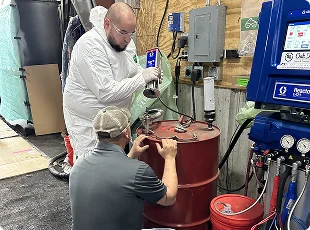 a man in white hazmat suit working on a red barrel