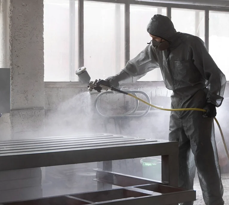 a man spraying a metal piece of furniture
