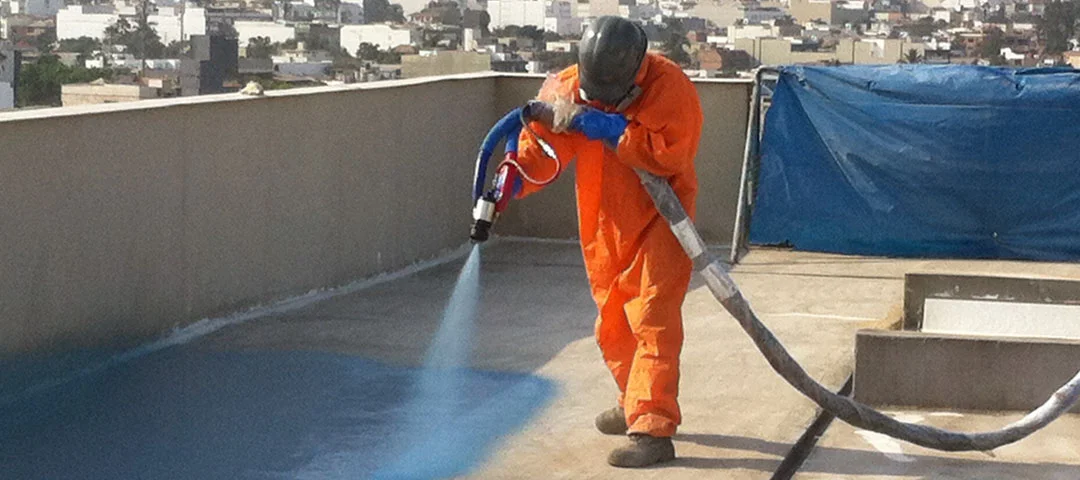 a person spraying blue paint on a roof